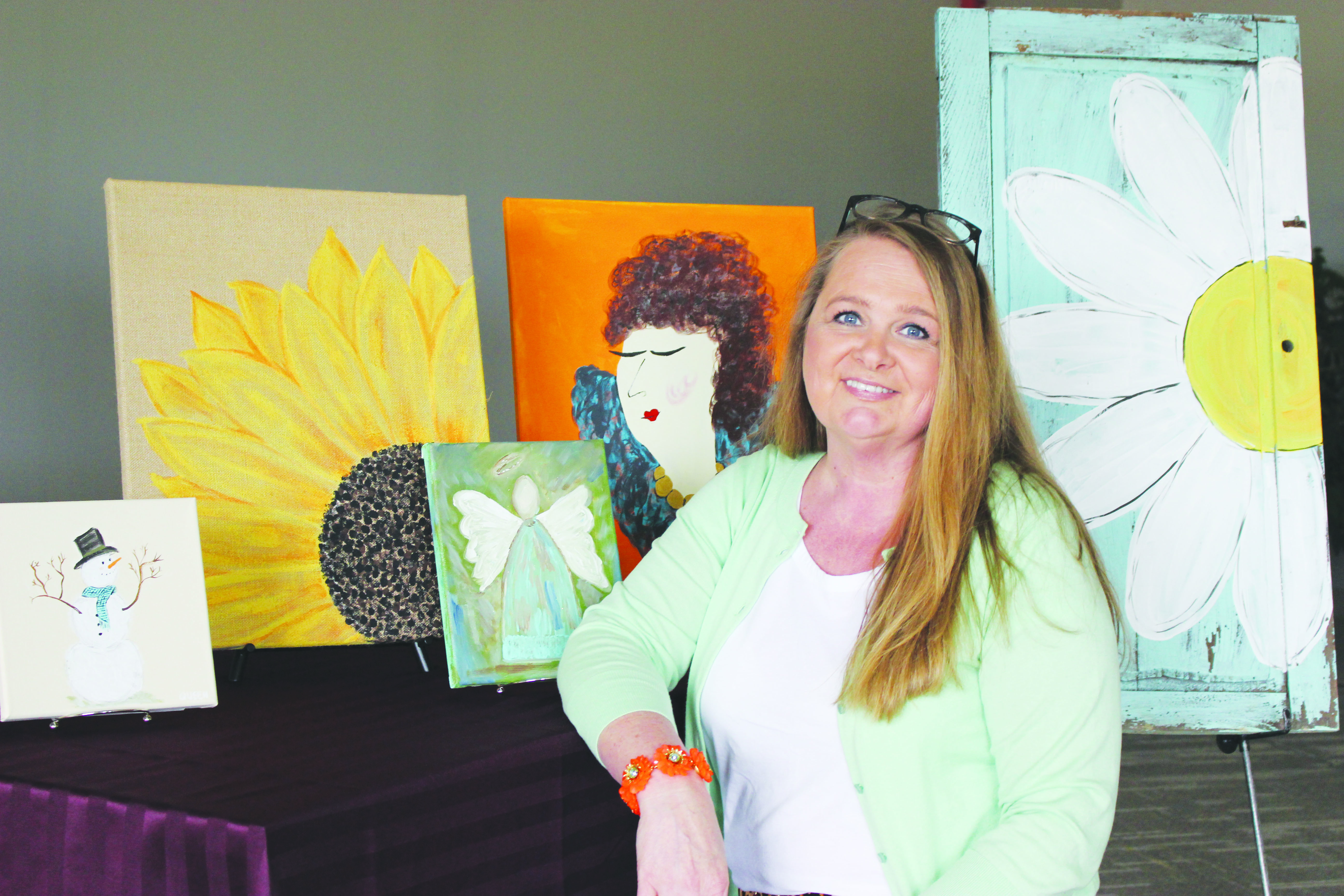Amy Queen is standing next to some of the paintings that were featured in her one-woman art show at Southern State College. Photo by Patricia Beech