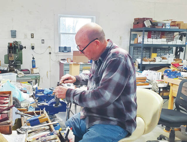 Cooper puts the final touches on a knife at his workstation. (Photo by Ashley McCarty)