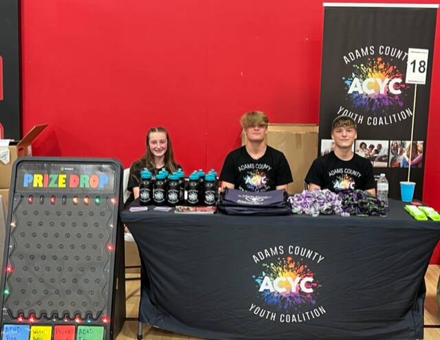 Adams County Youth Coalition - Olivia Poe, Braden and Damien McCann work their interactive booth at the Adams County Health Fair. (Photo by Sherry Larson)
