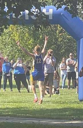 Raising his arms in triumph, Manchesters Connor Darnell crosses the finish line as the holder of the schools new boys cross-country record, finishing the race in a time of 16:53.1. (Photo provided)