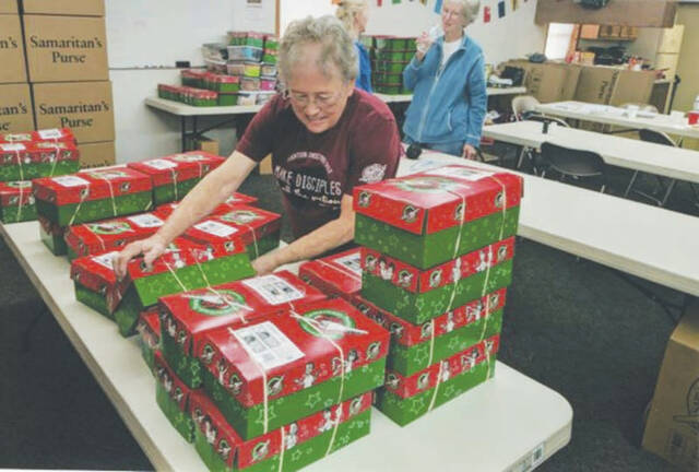 Sara Lewis sorting and organizing boxes to be placed into large shipping boxes. Boxes are sorted by size in order to get the most boxes in each of the large shipping containers. The range can go from 13 to 21, depending on the size of the shoebox.
