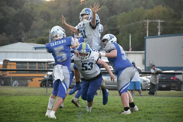 <p>Manchester’s Gage Stephens (53) goes low and teammate Remington Hayslip (51) goes airborne to disrupt this pass attempt from East quarterback Tanner Baughman. (Photo by Mark Carpenter)</p>