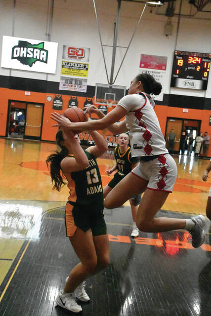 North Adams Ava Pistole (13) finds her path to the basket blocked by an airborne Portsmouth defender in action form the Lady Devils 55-32 loss in the district title game on February 28. (Photo by Mark Carpenter)