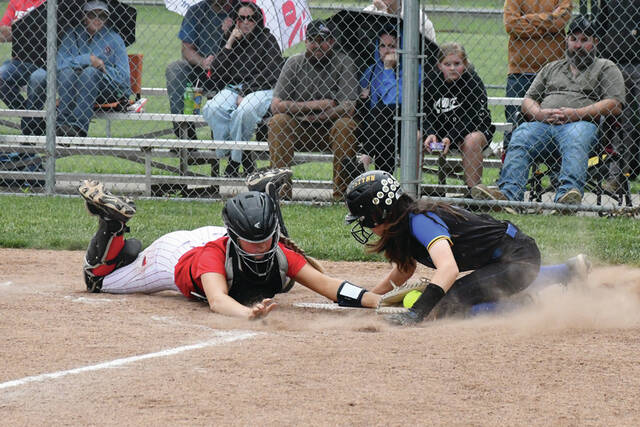 With an acrobatic slide, Manchesters Brislynn McClanahan (right) touches home plate before the tag of Peebles catcher Kendall Myers to score a run in the third inning of the two teams SHAC match up on May 5 at MHS. (Photo by Mark Carpenter)